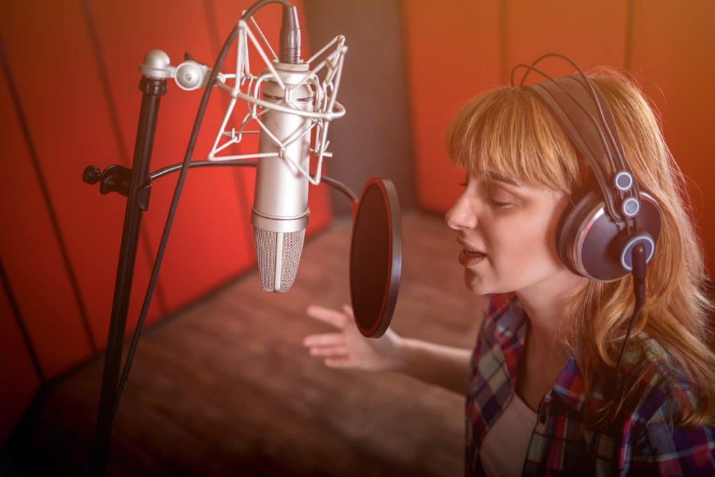 Female voice over actor performing in a recording studio
