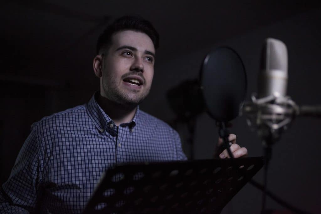 A male voice over actor performing in a studio