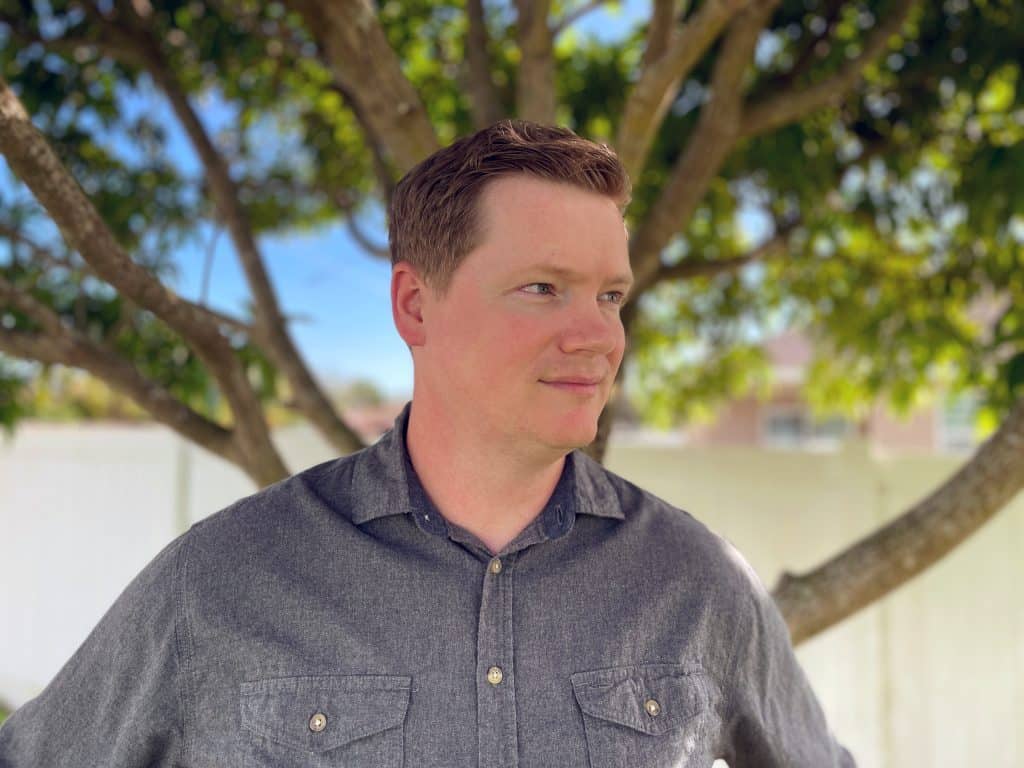 voice actor Mike Thomas standing outside under a mango tree