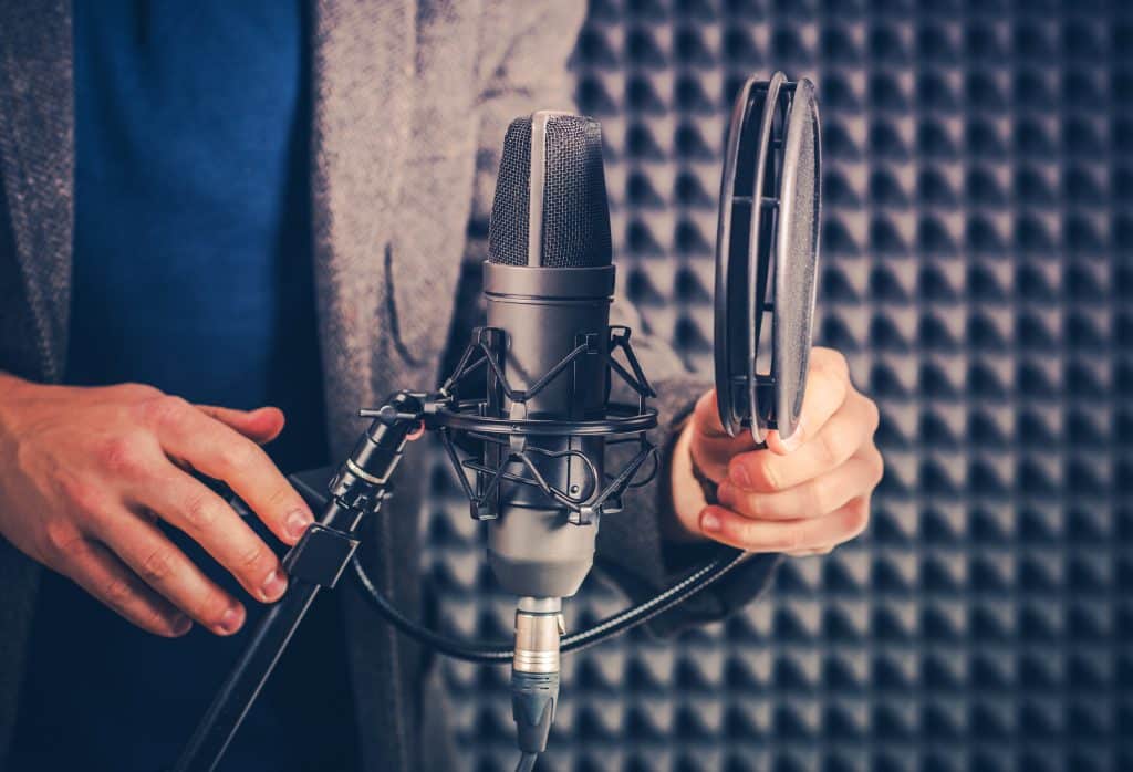 Male Voice Talent in the Studio Preparing Audio Recording Equipment For the Next Recording Session.